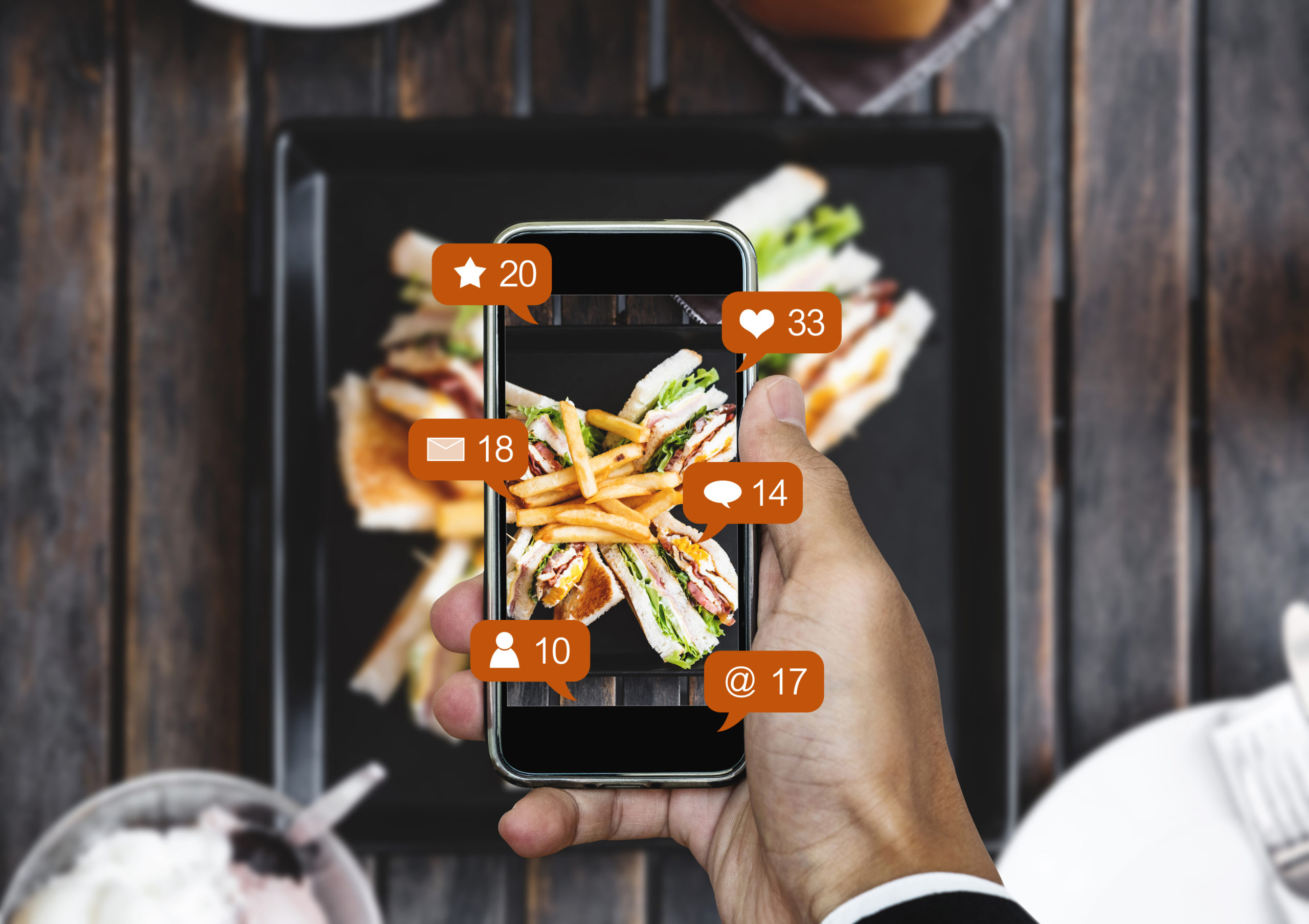 Restaurant food social media concept. Person taking a picture of their meal with social media icons around the camera screen