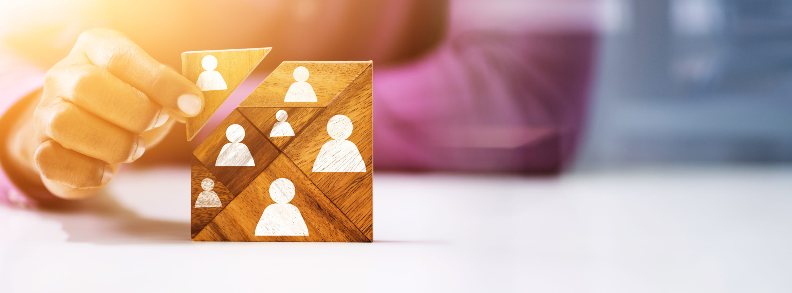 Close-up Of Man's Hand Holding A Missing Piece In A Square Tangram Puzzle symbolizing filling a team